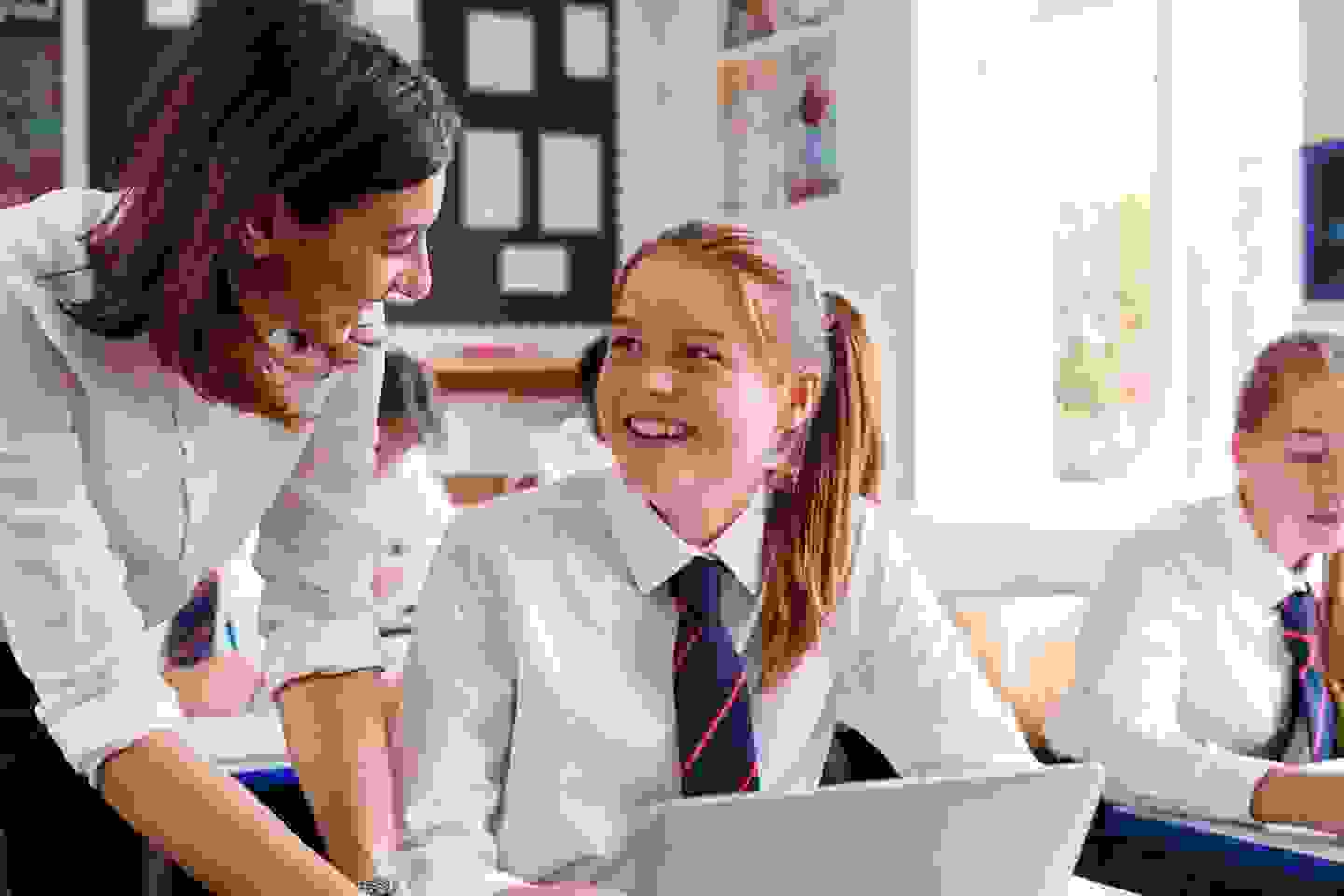 student-and-teacher-smiling-in-classroom.jpg?width=1440&quality=80 1440w