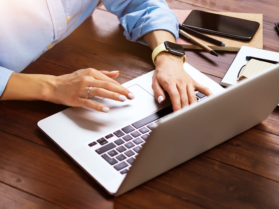 a top down shot of a woman taping on a laptop on a desk