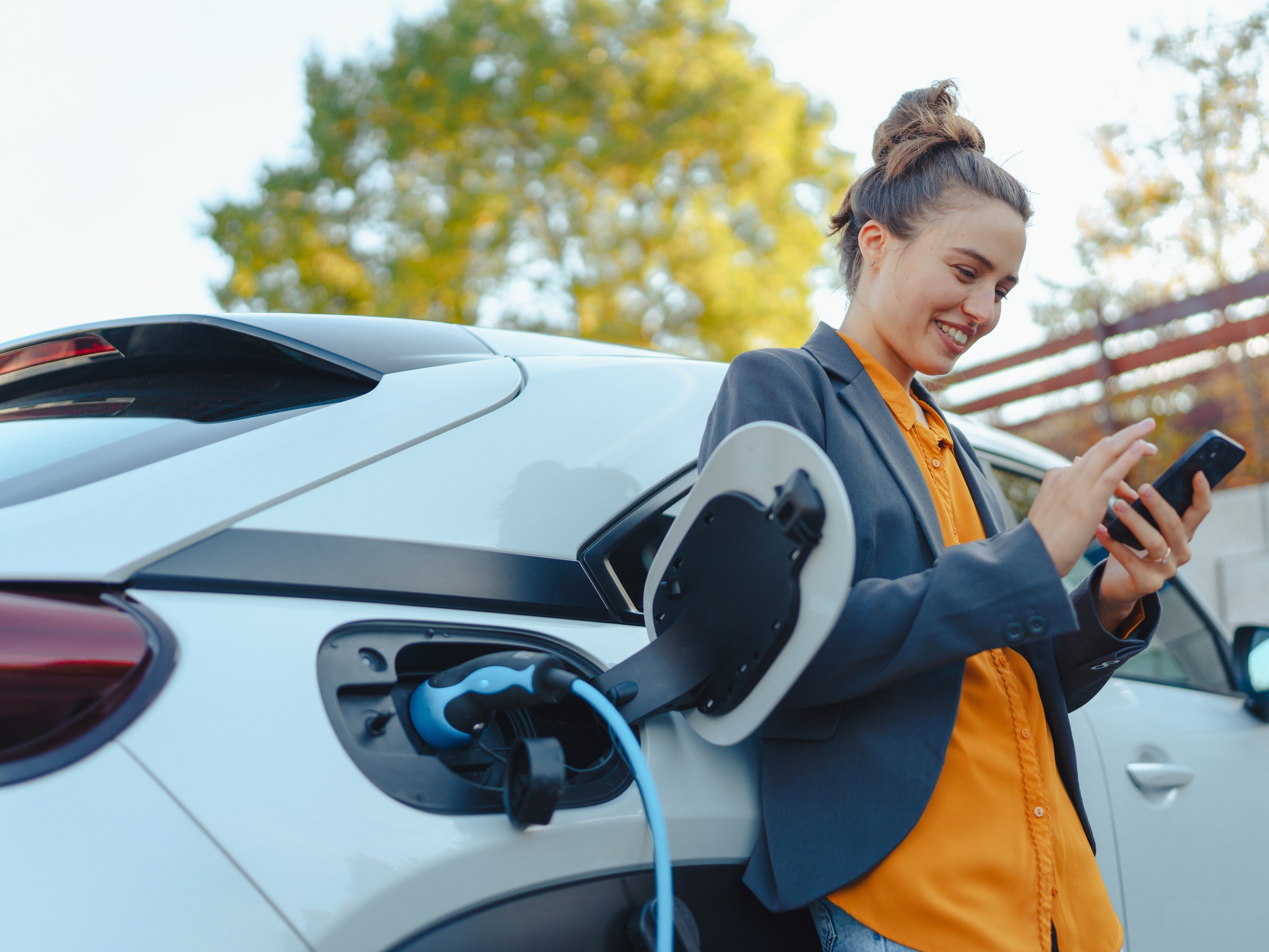 Person charging an electric vehicle while using their phone