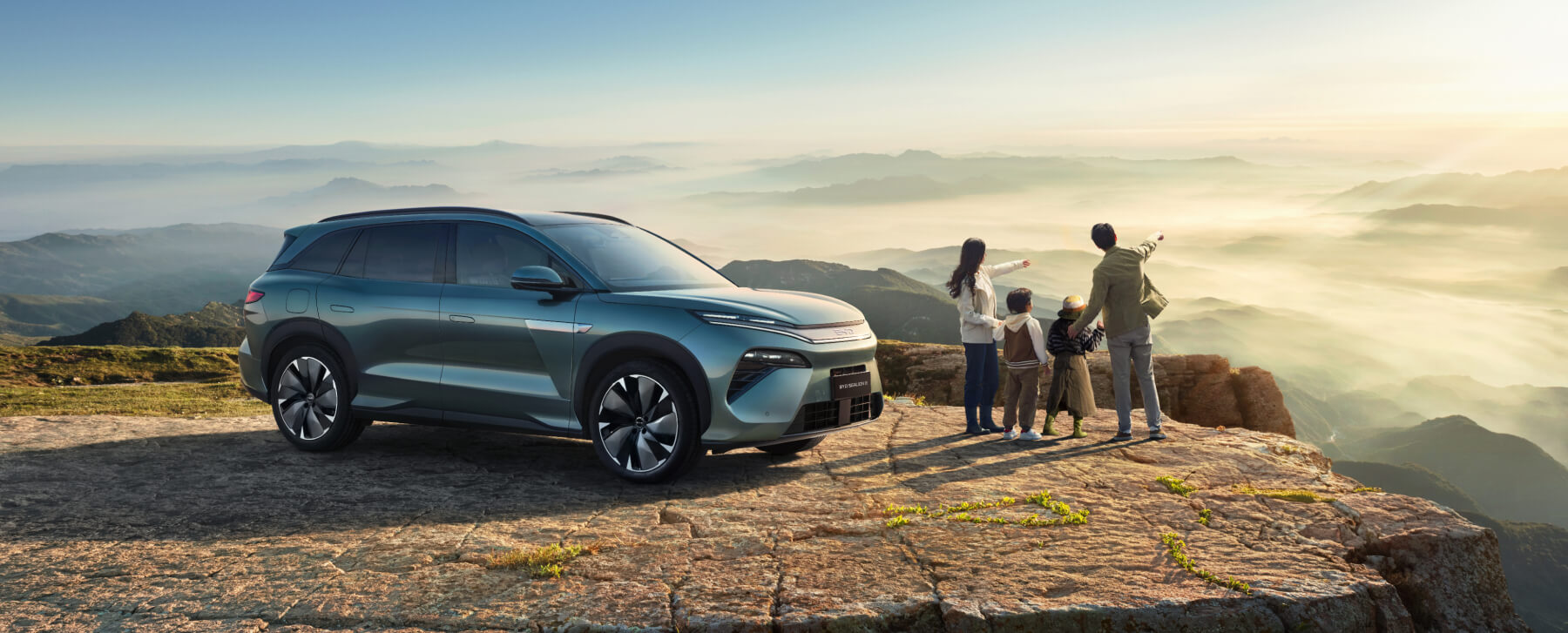 SUV parked on a mountain lookout with people viewing the landscape