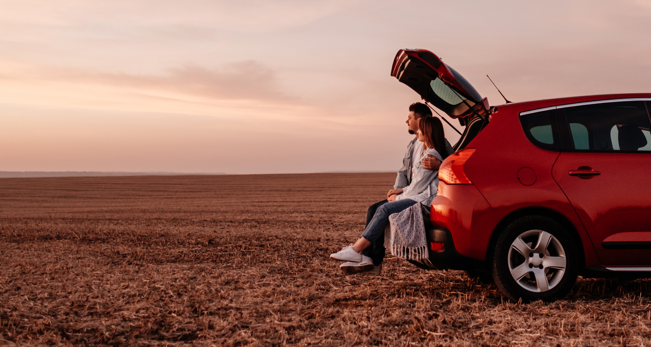 Couple sitting in boot of car