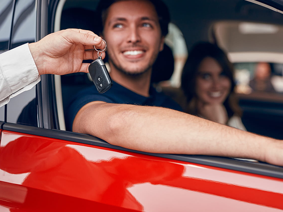 Person receiving car keys while seated in a vehicle, illustrating the final step of acquiring a car through a novated lease