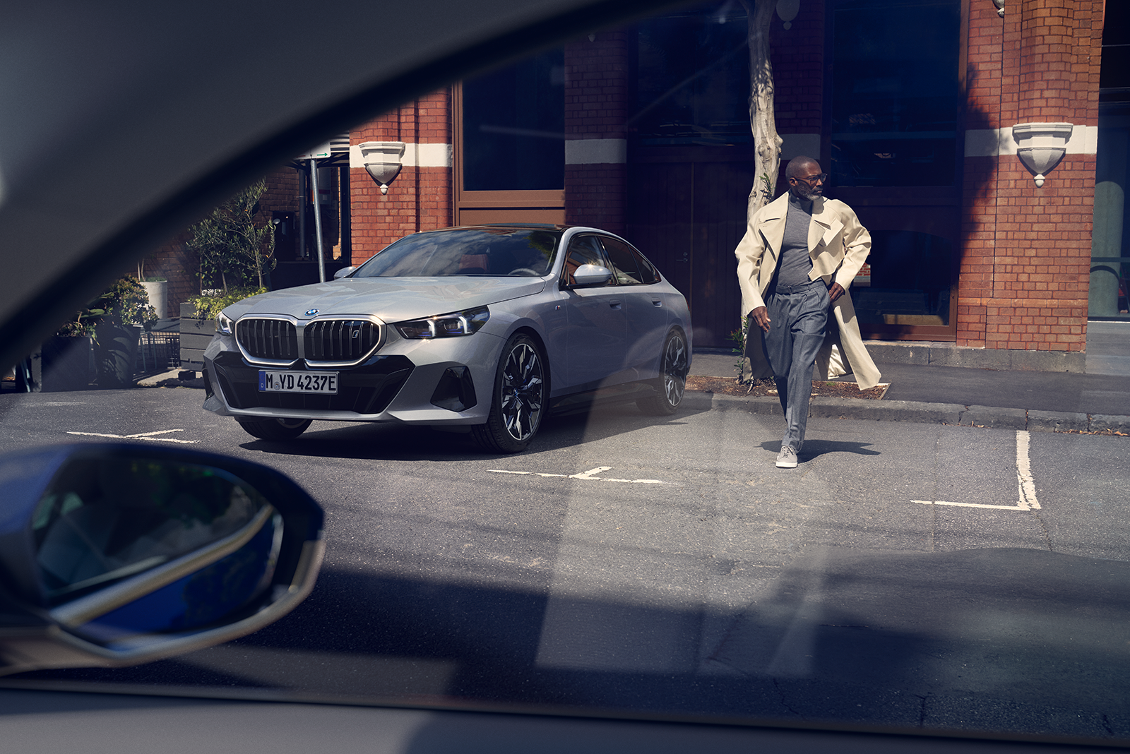 Man crossing street next to parked BMW