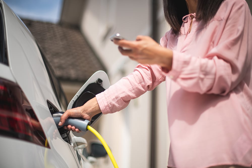 A woman plugging in an EV to charge