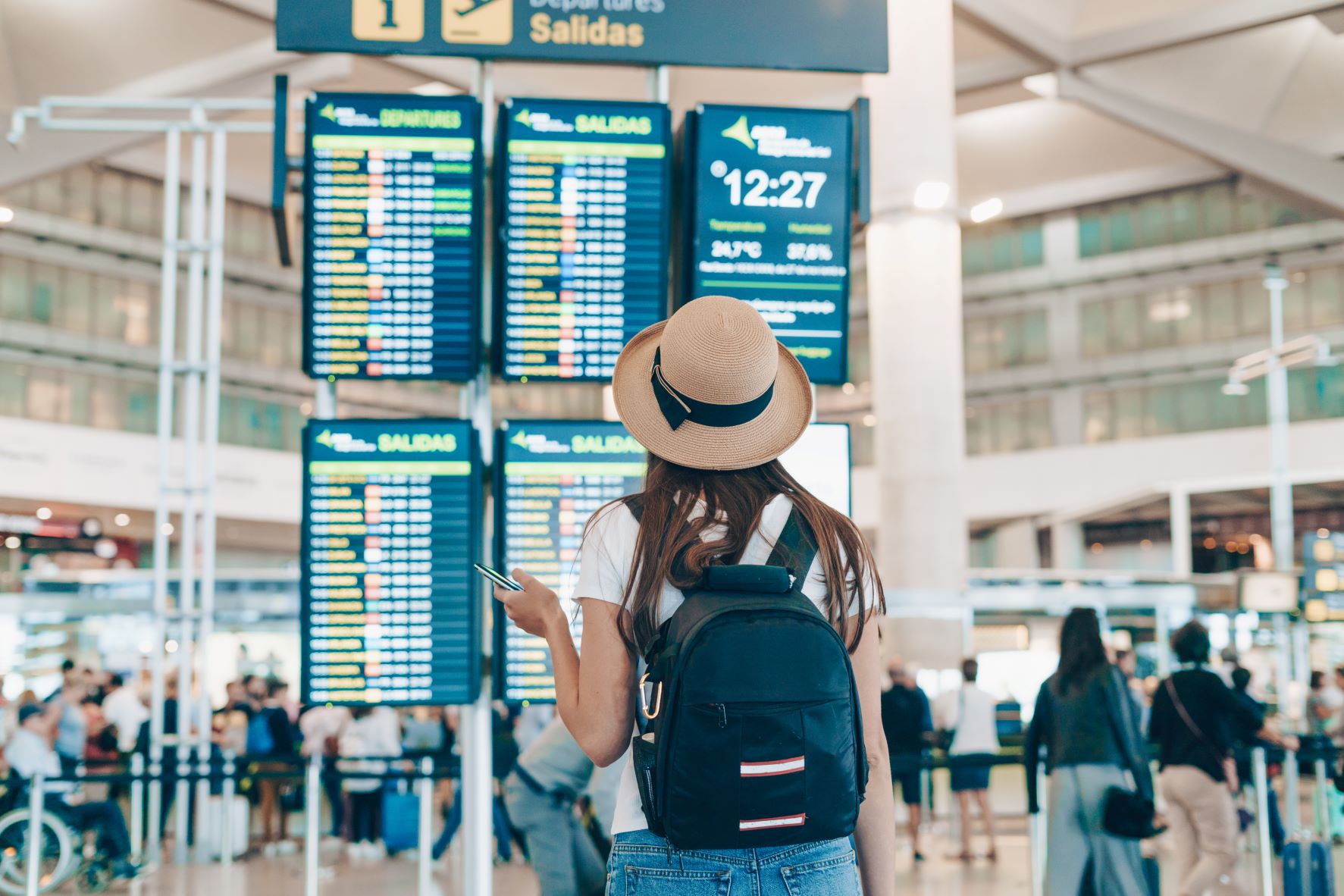 Women in a hat looking at her flight times  at the airport